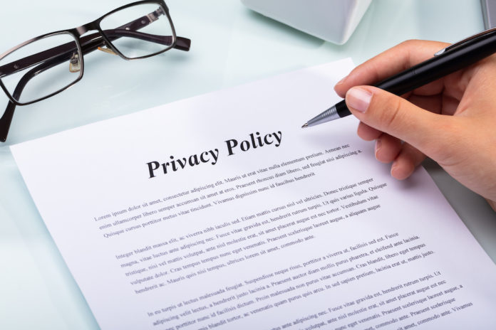 Close-up Of A Woman's Hand Holding Pen Over Privacy Policy Form